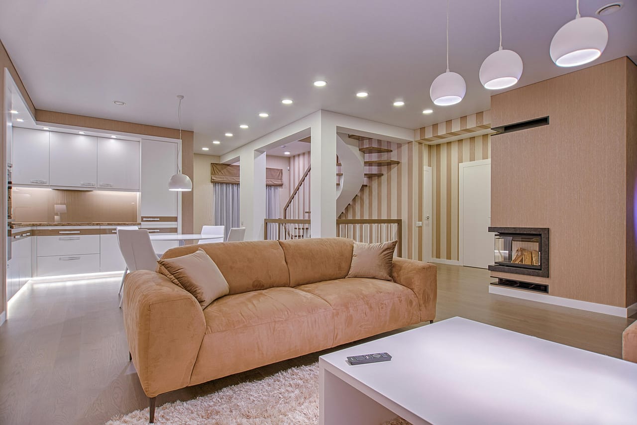 A beautifully lit modern living room in the evening, showcasing smart lighting control.